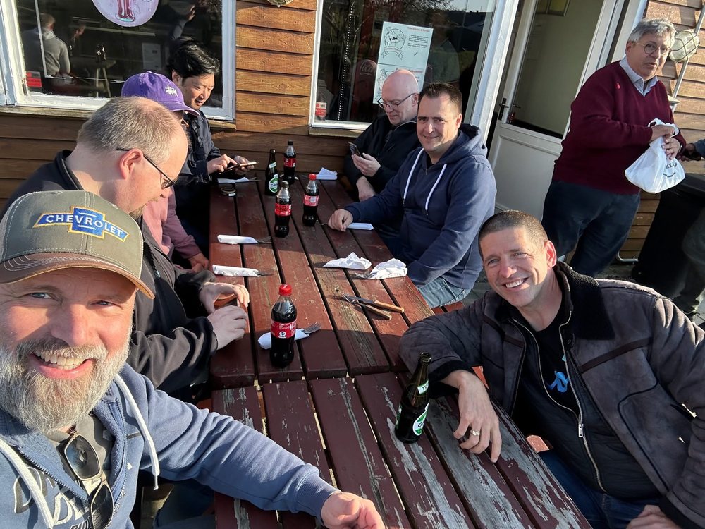 The crew around a long table outside the pizzeria in the spring sun